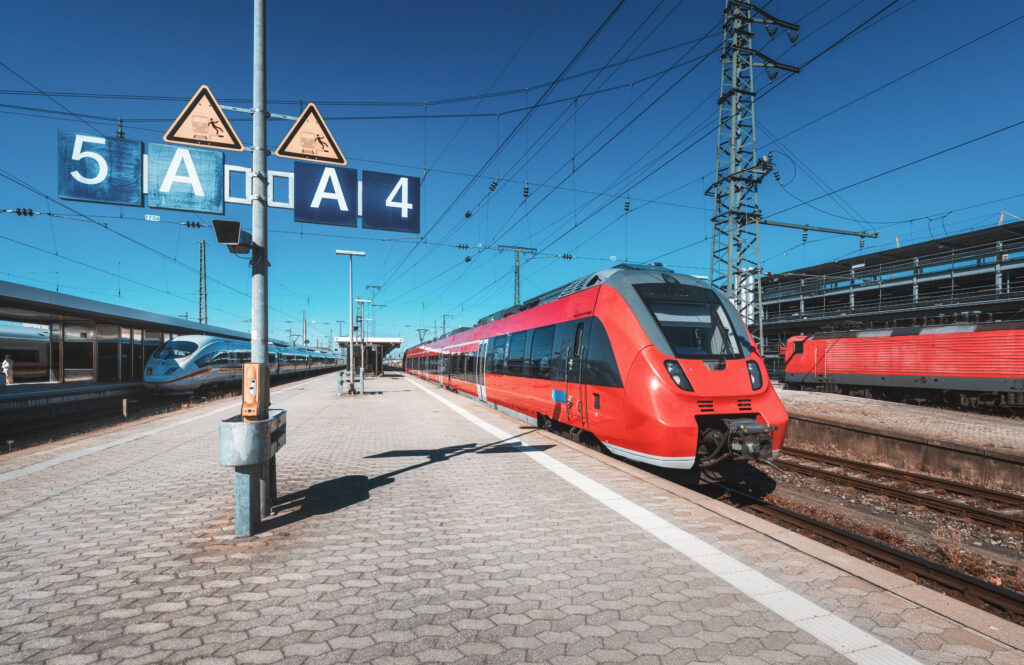 Bahnsteig mit Abschnitt A und rotem Zug.