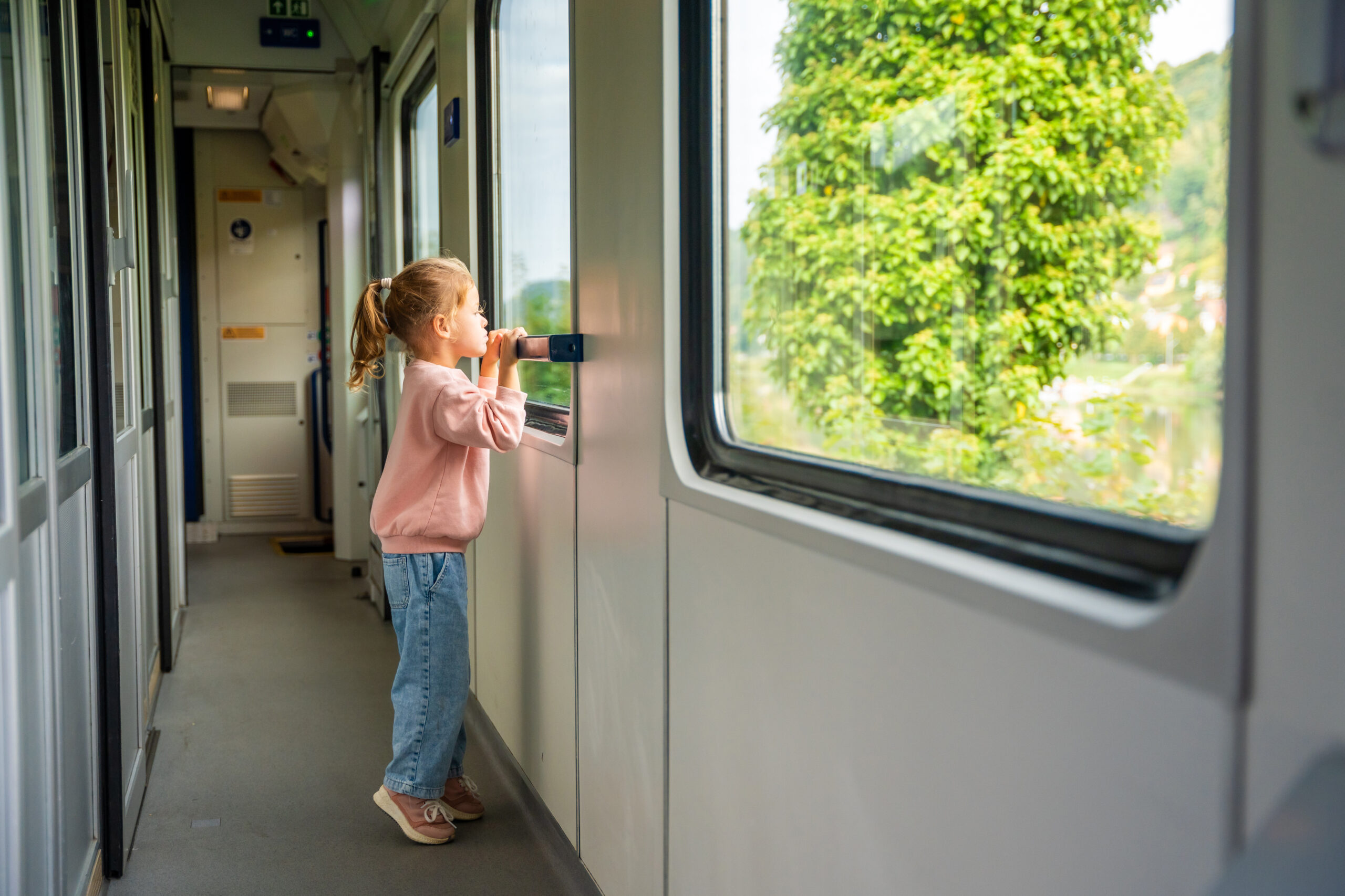 Kind im Kindergartenalter blickt aus fahrendem Zug