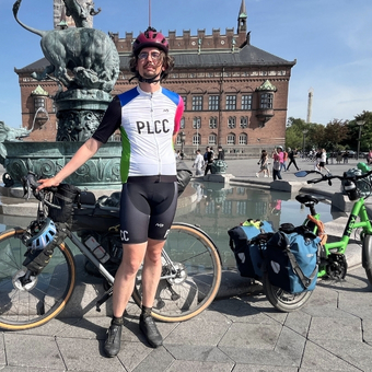 Radtouren-Checker Markus Vogt mit seinem Gravelbike vor dem Drachenbrunnen in Kopenhagen. Daneben ein grünes Kompakt E-Bike